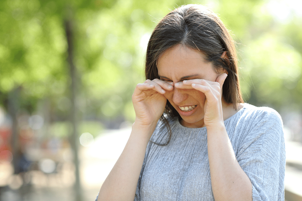 Woman experiencing eye pain outside