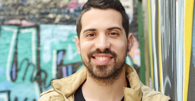 Man outside with urban graffiti in the background